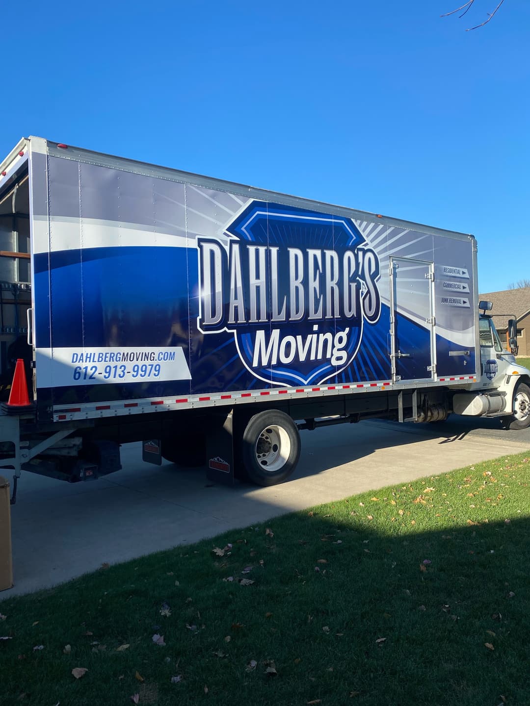 Dahlberg's Moving truck parked outside, featuring contact information and a clear blue sky.